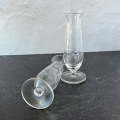 Pair of vintage Avon etched glass pedestal vases with frosted floral design and flared rim.