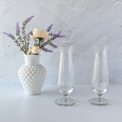 Pair of vintage Avon etched glass pedestal vases with frosted floral design and flared rim.