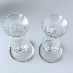 Pair of vintage Avon etched glass pedestal vases with frosted floral design and flared rim.