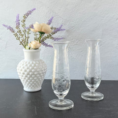 Pair of vintage Avon etched glass pedestal vases with frosted floral design and flared rim.