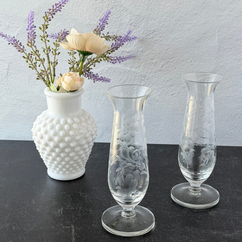 Pair of vintage Avon etched glass pedestal vases with frosted floral design and flared rim.