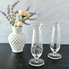 Pair of vintage Avon etched glass pedestal vases with frosted floral design and flared rim.