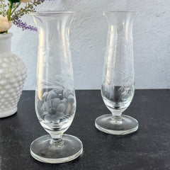 Pair of vintage Avon etched glass pedestal vases with frosted floral design and flared rim.