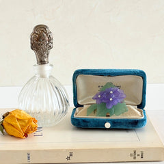Vintage 1983 Avon brooch with frosted purple resin violets, green leaves, and faux‑pearl centers.