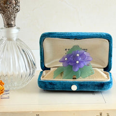Vintage 1983 Avon brooch with frosted purple resin violets, green leaves, and faux‑pearl centers.