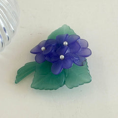 Vintage 1983 Avon brooch with frosted purple resin violets, green leaves, and faux‑pearl centers.