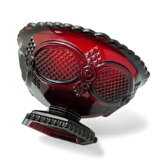 Vintage Avon ruby red glass compote with scalloped rim and pedestal base, featuring embossed Cape Cod pattern and rich crimson hue; a collectible 1970s–1990s candy dish styled for festive tables or vintage decor.