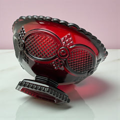 Vintage Avon ruby red glass compote with scalloped rim and pedestal base, featuring embossed Cape Cod pattern and rich crimson hue; a collectible 1970s–1990s candy dish styled for festive tables or vintage decor.