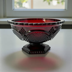 Vintage Avon ruby red glass compote with scalloped rim and pedestal base, featuring embossed Cape Cod pattern and rich crimson hue; a collectible 1970s–1990s candy dish styled for festive tables or vintage decor.