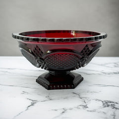 Vintage Avon ruby red glass compote with scalloped rim and pedestal base, featuring embossed Cape Cod pattern and rich crimson hue; a collectible 1970s–1990s candy dish styled for festive tables or vintage decor.
