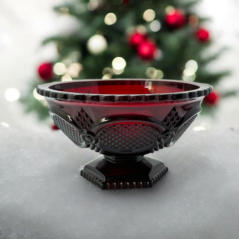 Vintage Avon ruby red glass compote with scalloped rim and pedestal base, featuring embossed Cape Cod pattern and rich crimson hue; a collectible 1970s–1990s candy dish styled for festive tables or vintage decor.