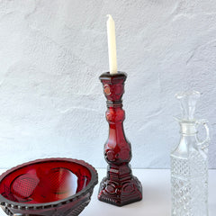 Vintage Avon 1876 Cape Cod Collection ruby red glass perfume bottle and candlestick holder with hexagonal base and ornate embossed pattern, shown with matching bowl and clear decanter.