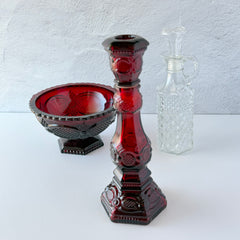 Vintage Avon 1876 Cape Cod Collection ruby red glass perfume bottle and candlestick holder with hexagonal base and ornate embossed pattern, shown with matching bowl and clear decanter.