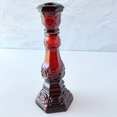 Vintage Avon 1876 Cape Cod Collection ruby red glass perfume bottle and candlestick holder with hexagonal base and ornate embossed pattern.