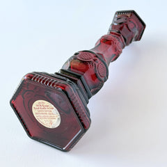 Vintage Avon 1876 Cape Cod Collection ruby red glass perfume bottle and candlestick holder with hexagonal base and ornate embossed pattern.