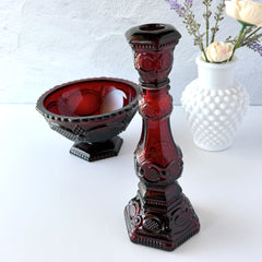 Vintage Avon 1876 Cape Cod Collection ruby red glass perfume bottle and candlestick holder with hexagonal base and ornate embossed pattern, shown with matching bowl and white vase.