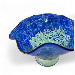 Signed BAGI art glass bowl with a footed base and wavy rim, featuring mottled blue and green swirls. The glass has a glossy finish and sculptural form, with vibrant oceanic and forest tones. Dimensions approximately 5–5½" tall and 7–8" wide.