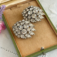 Vintage clear rhinestone clip‑on earrings with teardrop and chaton stones in a mid‑century silver tone fan‑cluster design.
