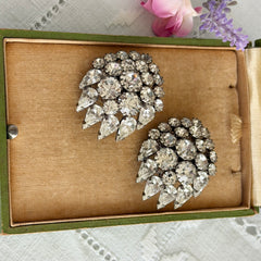 Vintage clear rhinestone clip‑on earrings with teardrop and chaton stones in a mid‑century silver tone fan‑cluster design.