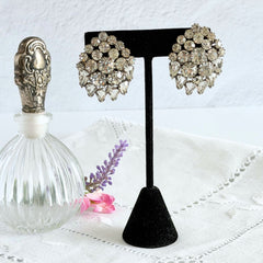 Vintage clear rhinestone clip‑on earrings with teardrop and chaton stones in a mid‑century silver tone fan‑cluster design.