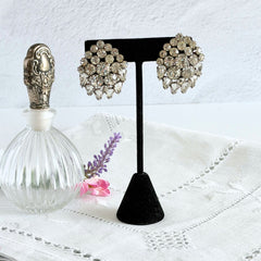 Vintage clear rhinestone clip‑on earrings with teardrop and chaton stones in a mid‑century silver tone fan‑cluster design.