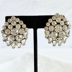 Vintage clear rhinestone clip‑on earrings with teardrop and chaton stones in a mid‑century silver tone fan‑cluster design.