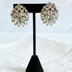 Vintage clear rhinestone clip‑on earrings with teardrop and chaton stones in a mid‑century silver tone fan‑cluster design.