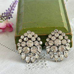 Vintage clear rhinestone clip‑on earrings with teardrop and chaton stones in a mid‑century silver tone fan‑cluster design.