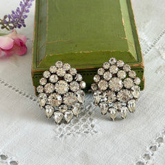 Vintage clear rhinestone clip‑on earrings with teardrop and chaton stones in a mid‑century silver tone fan‑cluster design.