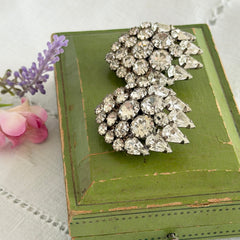 Vintage clear rhinestone clip‑on earrings with teardrop and chaton stones in a mid‑century silver tone fan‑cluster design.