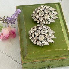 Vintage clear rhinestone clip‑on earrings with teardrop and chaton stones in a mid‑century silver tone fan‑cluster design.