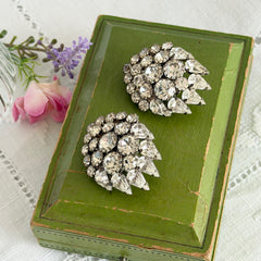 Vintage clear rhinestone clip‑on earrings with teardrop and chaton stones in a mid‑century silver tone fan‑cluster design.
