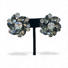 Vintage 1950s silver-tone clip-on earrings with black diamond and clear rhinestones in a radiant pinwheel design; unsigned but crafted with rivet and swedge construction typical of Beau Jewels or Judy Lee, approx. 1¼" diameter, in very good vintage condition with secure clips and brilliant sparkle.