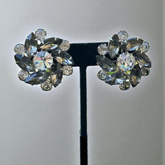 Vintage 1950s silver-tone clip-on earrings with black diamond and clear rhinestones in a radiant pinwheel design; unsigned but crafted with rivet and swedge construction typical of Beau Jewels or Judy Lee, approx. 1¼" diameter, in very good vintage condition with secure clips and brilliant sparkle.