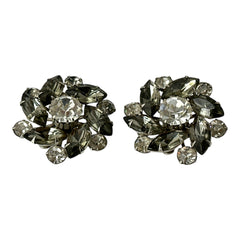 Vintage 1950s silver-tone clip-on earrings with black diamond and clear rhinestones in a radiant pinwheel design; unsigned but crafted with rivet and swedge construction typical of Beau Jewels or Judy Lee, approx. 1¼" diameter, in very good vintage condition with secure clips and brilliant sparkle.