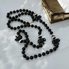 Vintage 1990s necklace featuring a symmetrical design with two elephant-shaped black beads, two black-and-white beads resembling banded agate, and a strand of 8mm black plastic beads in very good condition