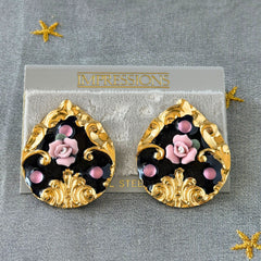 Vintage 1980s teardrop post earrings with 3D pink polymer clay rose, black enamel base, and gold tone pressed metal scrollwork on original card.