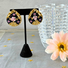 Vintage 1980s teardrop post earrings with 3D pink polymer clay rose, black enamel base, and gold tone pressed metal scrollwork on original card.