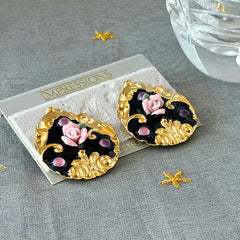 Vintage 1980s teardrop post earrings with 3D pink polymer clay rose, black enamel base, and gold tone pressed metal scrollwork on original card.