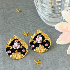 Vintage 1980s teardrop post earrings with 3D pink polymer clay rose, black enamel base, and gold tone pressed metal scrollwork on original card.