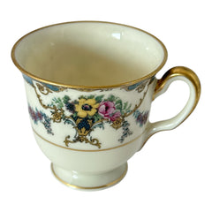 Vintage Black Knight Hohenberg Bavaria porcelain demi-tasse teacup in Monceau pattern; white base with multicolored floral design, teal and gold scrollwork near rim, and gold-trimmed handle and pedestal base.