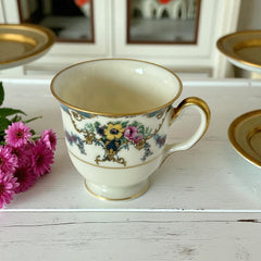 Vintage Black Knight Hohenberg Bavaria porcelain demi-tasse teacup in Monceau pattern; white base with multicolored floral design, teal and gold scrollwork near rim, and gold-trimmed handle and pedestal base.