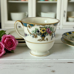 Vintage Black Knight Hohenberg Bavaria porcelain demi-tasse teacup in Monceau pattern; white base with multicolored floral design, teal and gold scrollwork near rim, and gold-trimmed handle and pedestal base.