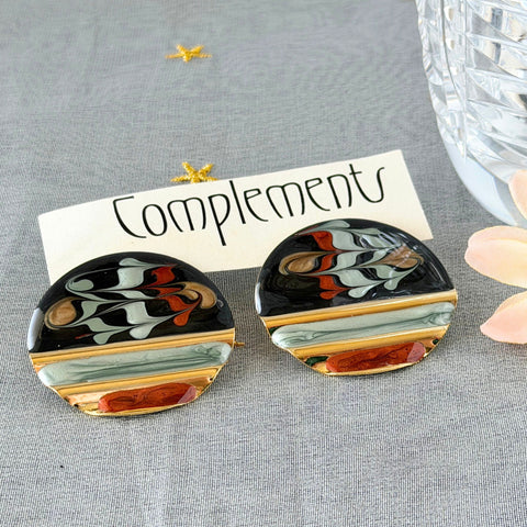 Vintage 1980s black, green, and rust enamel geometric gold‑tone circle post earrings on original Complements card, shown on grey fabric background.