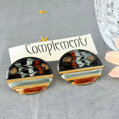Vintage 1980s black, green, and rust enamel geometric gold‑tone circle post earrings on original Complements card, shown on grey fabric background.
