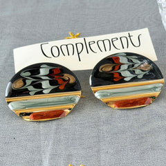 Vintage 1980s black, green, and rust enamel geometric gold‑tone circle post earrings on original Complements card, shown on grey fabric background.
