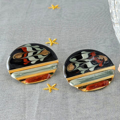 Vintage 1980s black, green, and rust enamel geometric gold‑tone circle post earrings on original Complements card, shown on grey fabric background.