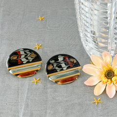 Vintage 1980s black, green, and rust enamel geometric gold‑tone circle post earrings on original Complements card, shown on grey fabric background.