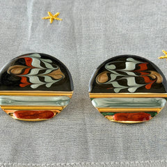 Vintage 1980s black, green, and rust enamel geometric gold‑tone circle post earrings on original Complements card, shown on grey fabric background.