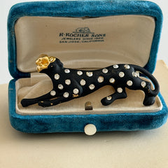 Black matte enamel panther brooch with clear rhinestones and gold tone accents, vintage 1990s animal jewelry.